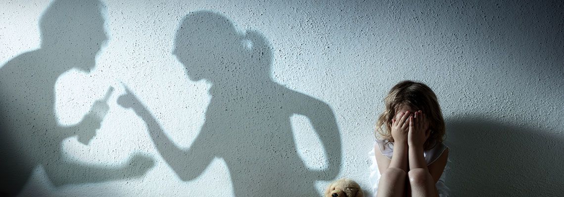Crying child with silhouettes of parents fighting