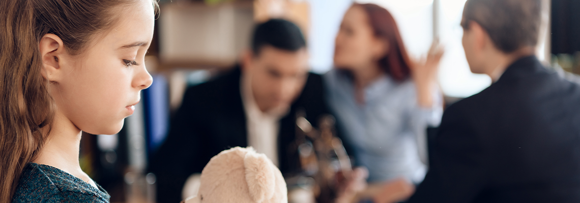 Upset girl with a bear in hand is standing and sad