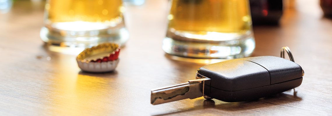Drinking and driving. Car key on a wooden bar counter