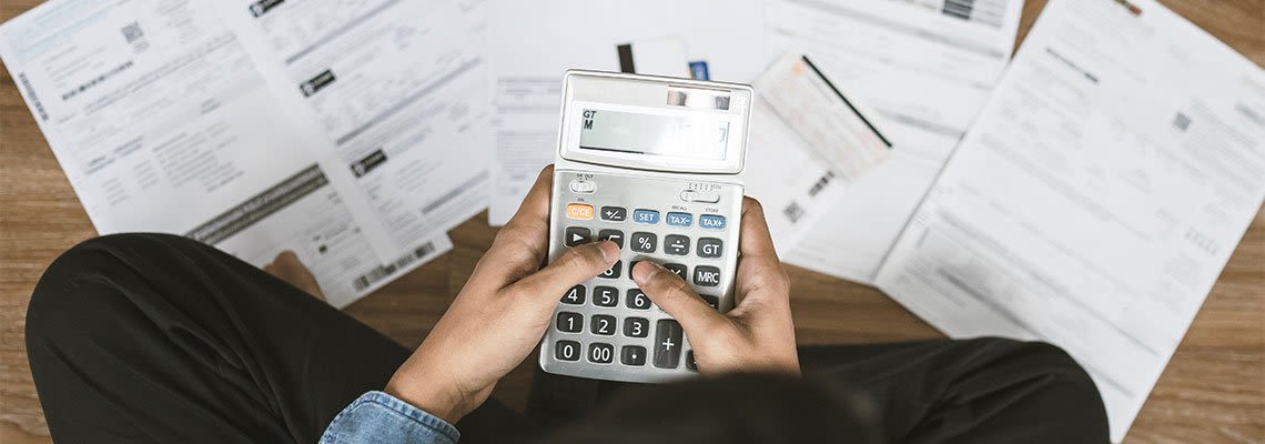 Person holding a calculator and reviewing papers