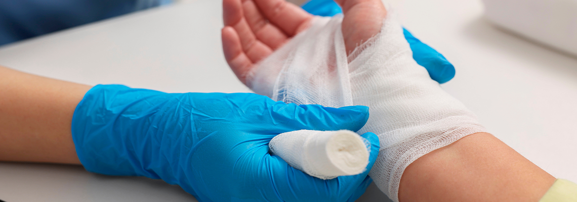 Doctor bandaging patient's burned hand indoors, closeup