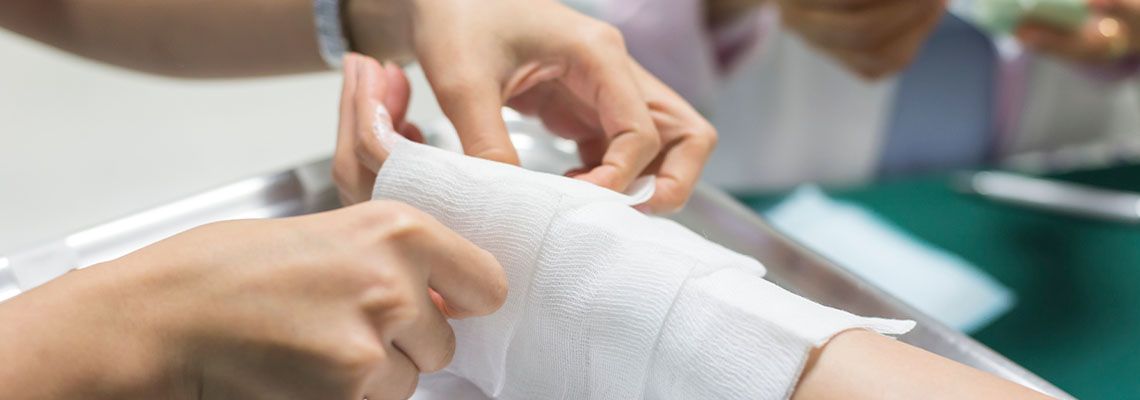 Nurse applying bandage to burn hand of patient