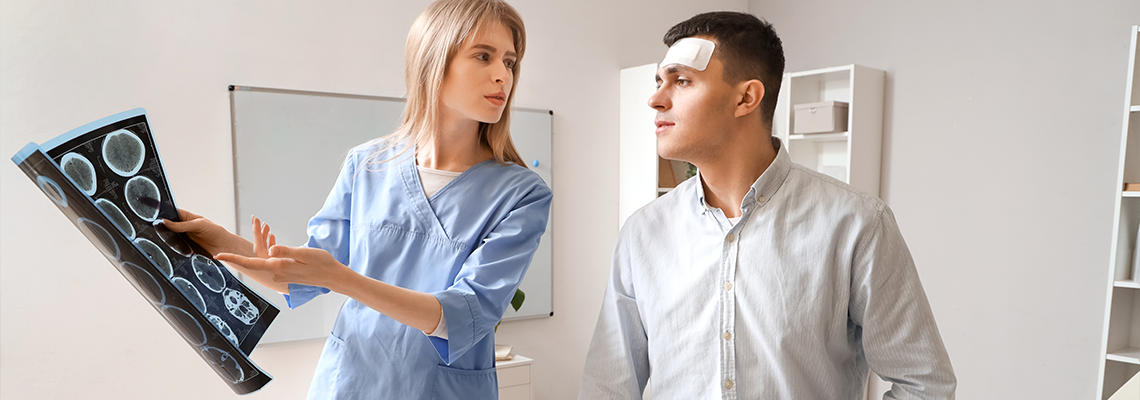 Female doctor and man with brain concussion examining MRI scan in clinic