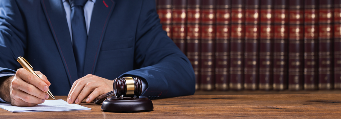 Man Signing Documents Next to a Gavel