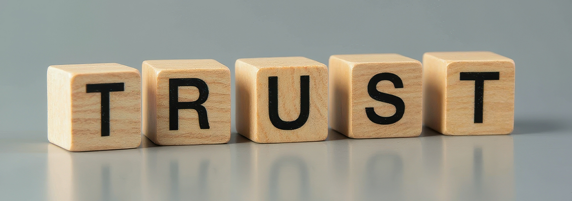 Four wooden cubes spelling trust on reflective surface