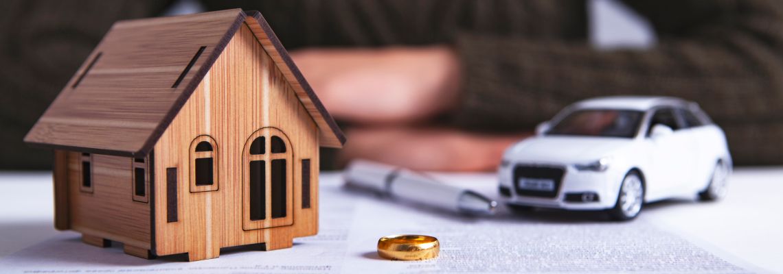 Wedding ring on divorce paper with car and house model