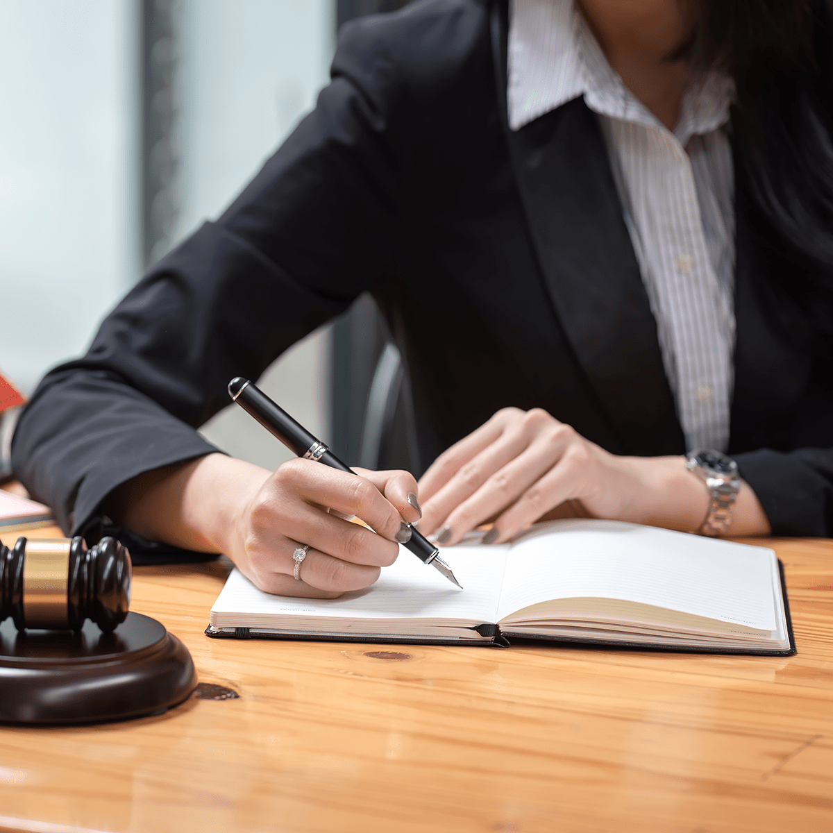 Close-up of a woman lawyer holding a pen with a notebook at the office.