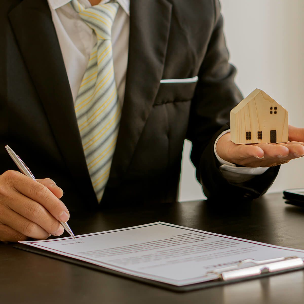 Business man at his desk holding a wooden house