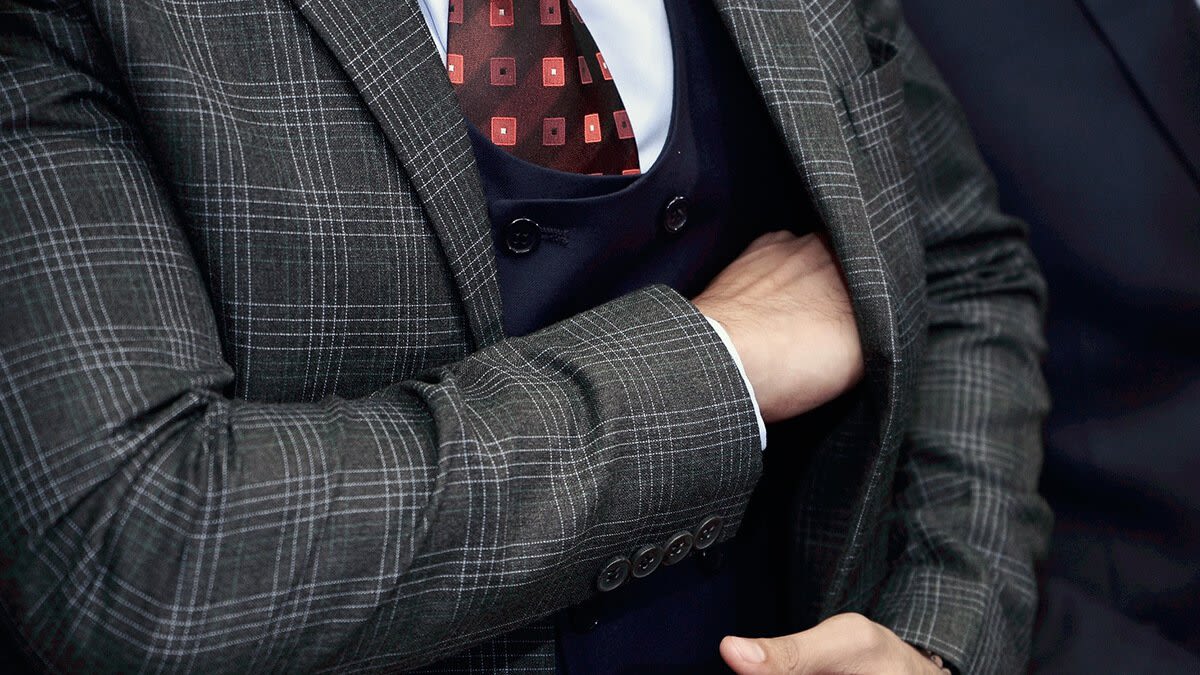 Man in suit reaching into his coat pocket