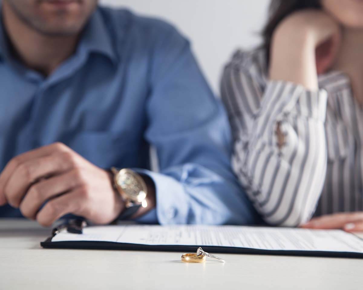 A couple going through divorce documents with their rings on the table