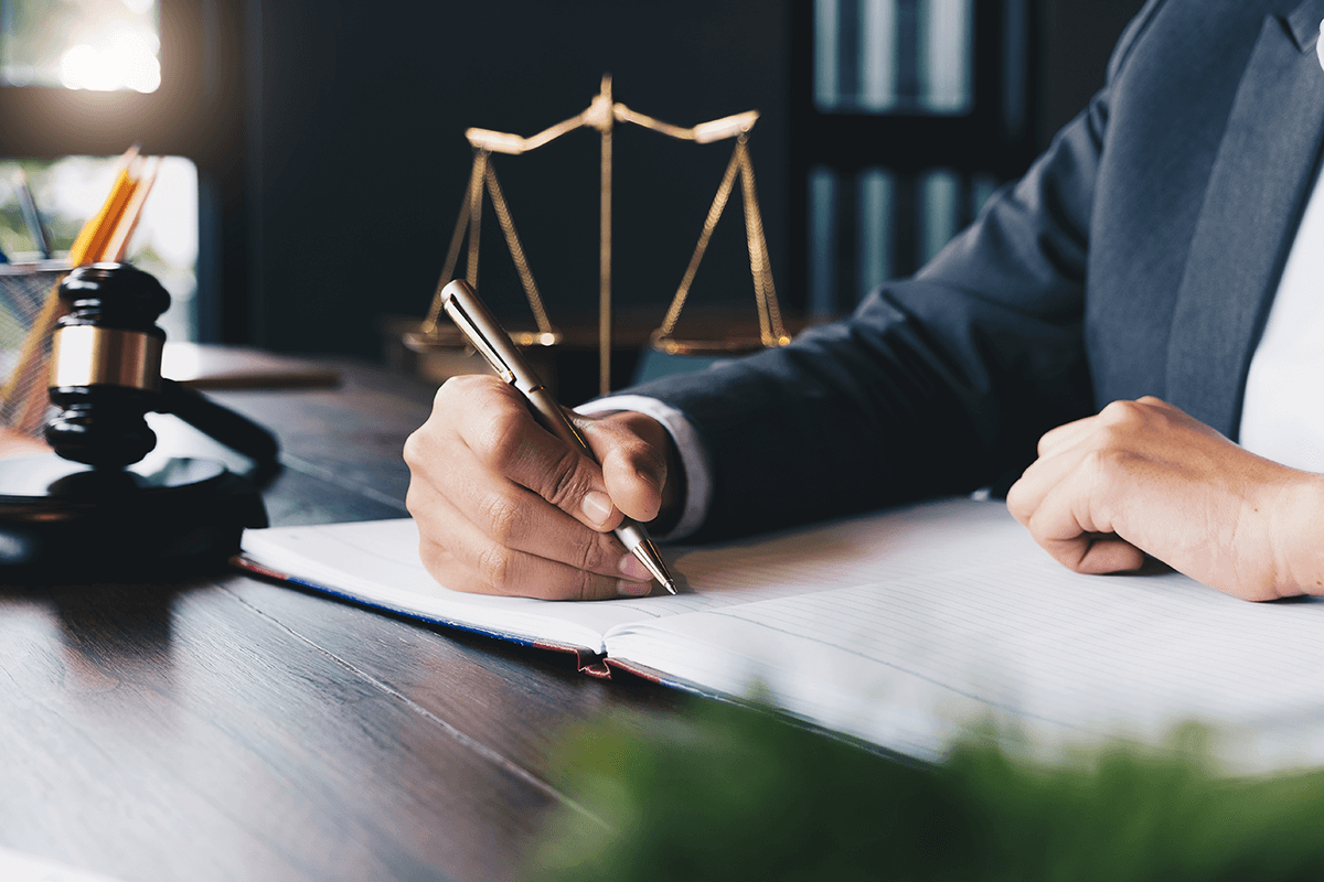 A lawyer is at his desk, writing in his booklet