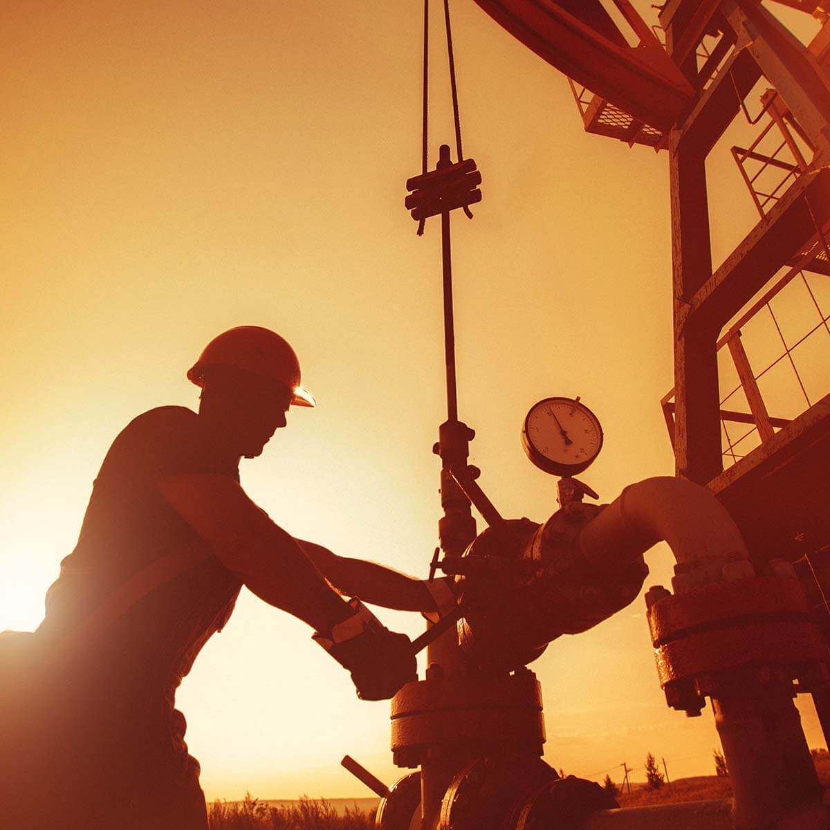 Oil worker is checking the oil pump on the sunset background