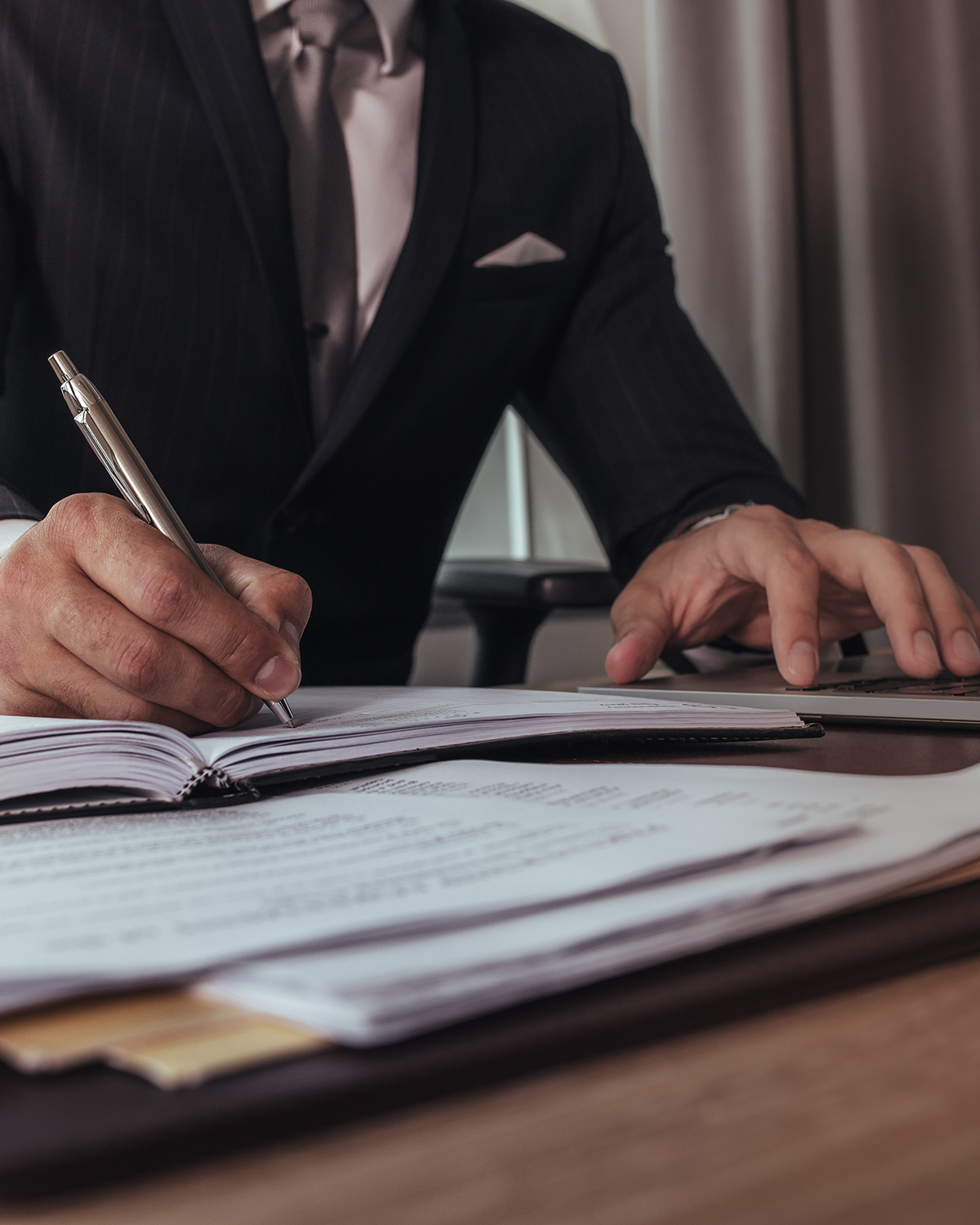 An attorney writing at his desk while typing.