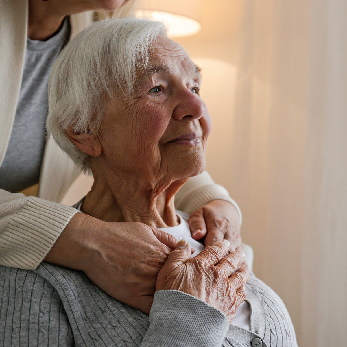 An elder woman holding her daughter's hands.