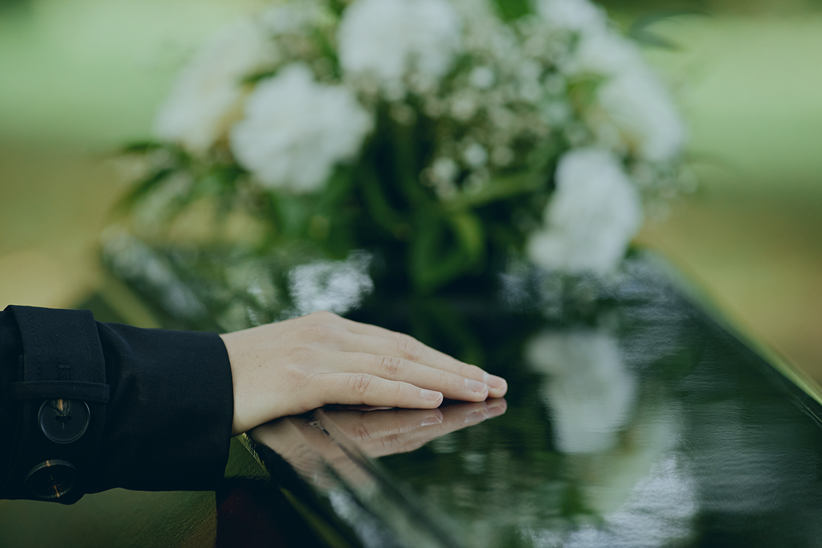 A woman placing her hand on a casket.