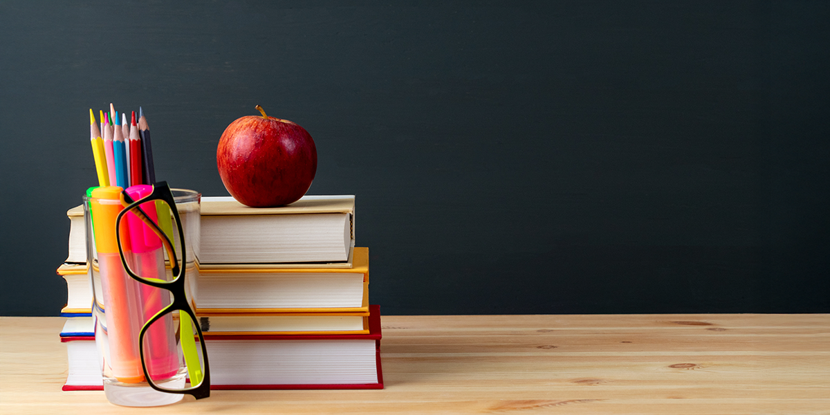 A stack of books and teaching supplies on a desk.