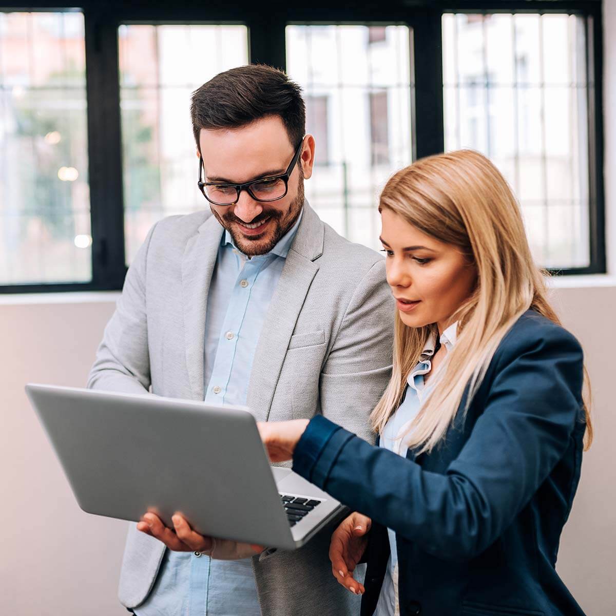 Two coworkers looking at a laptop together.