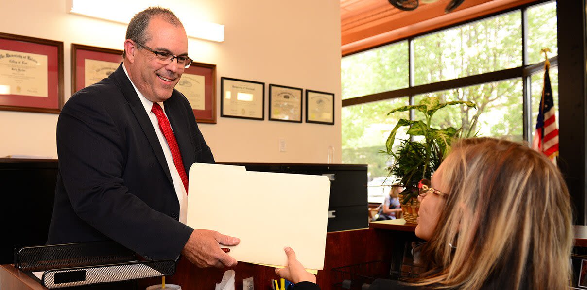 Attorney Richard Hyde handing a folder to a woman sitting down