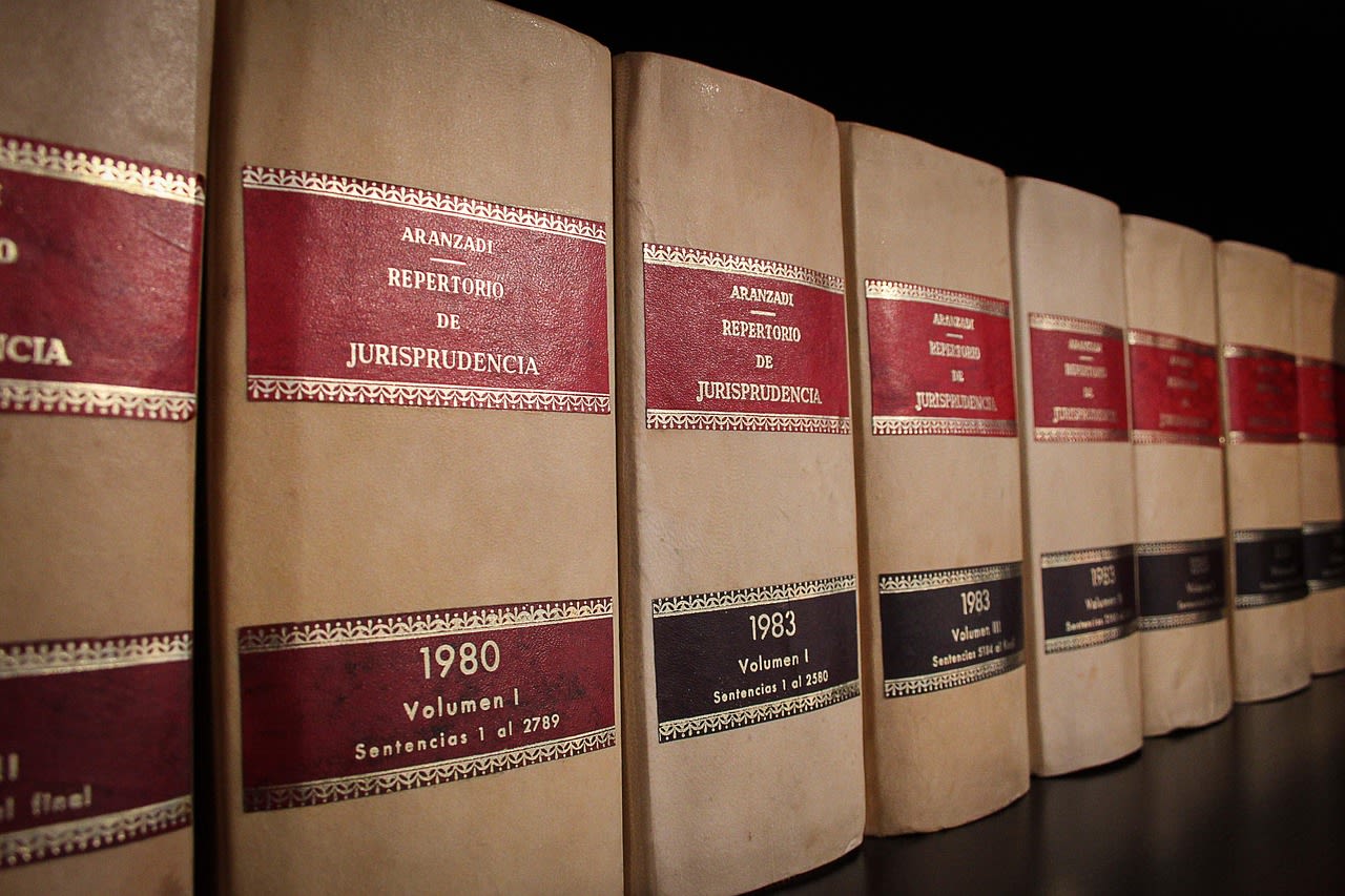 Jurisprudence law books lined up on a shelf, representing legal research and an attorney’s professional background.