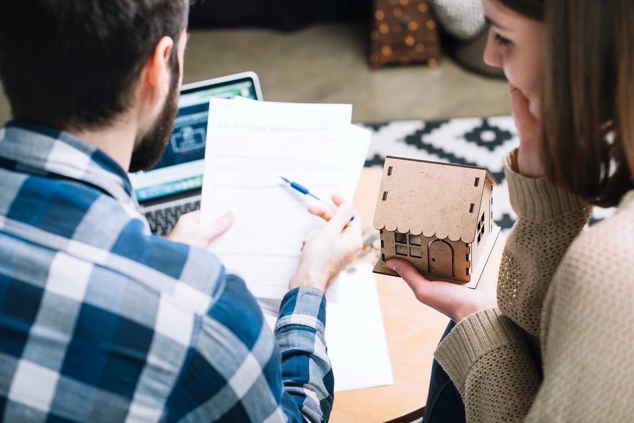 Couple reviewing estate planning documents while holding a model house