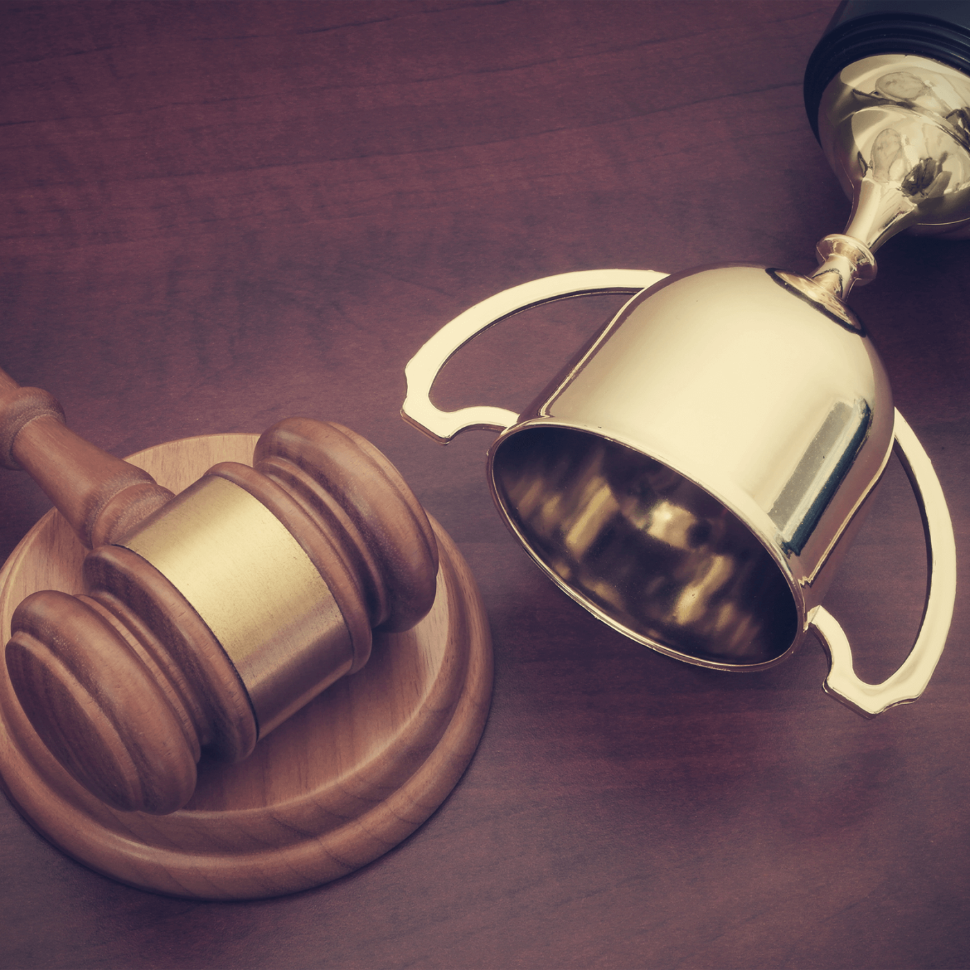 Gold trophy cup and wooden gavel on brown background, court of arbitration for sport concept