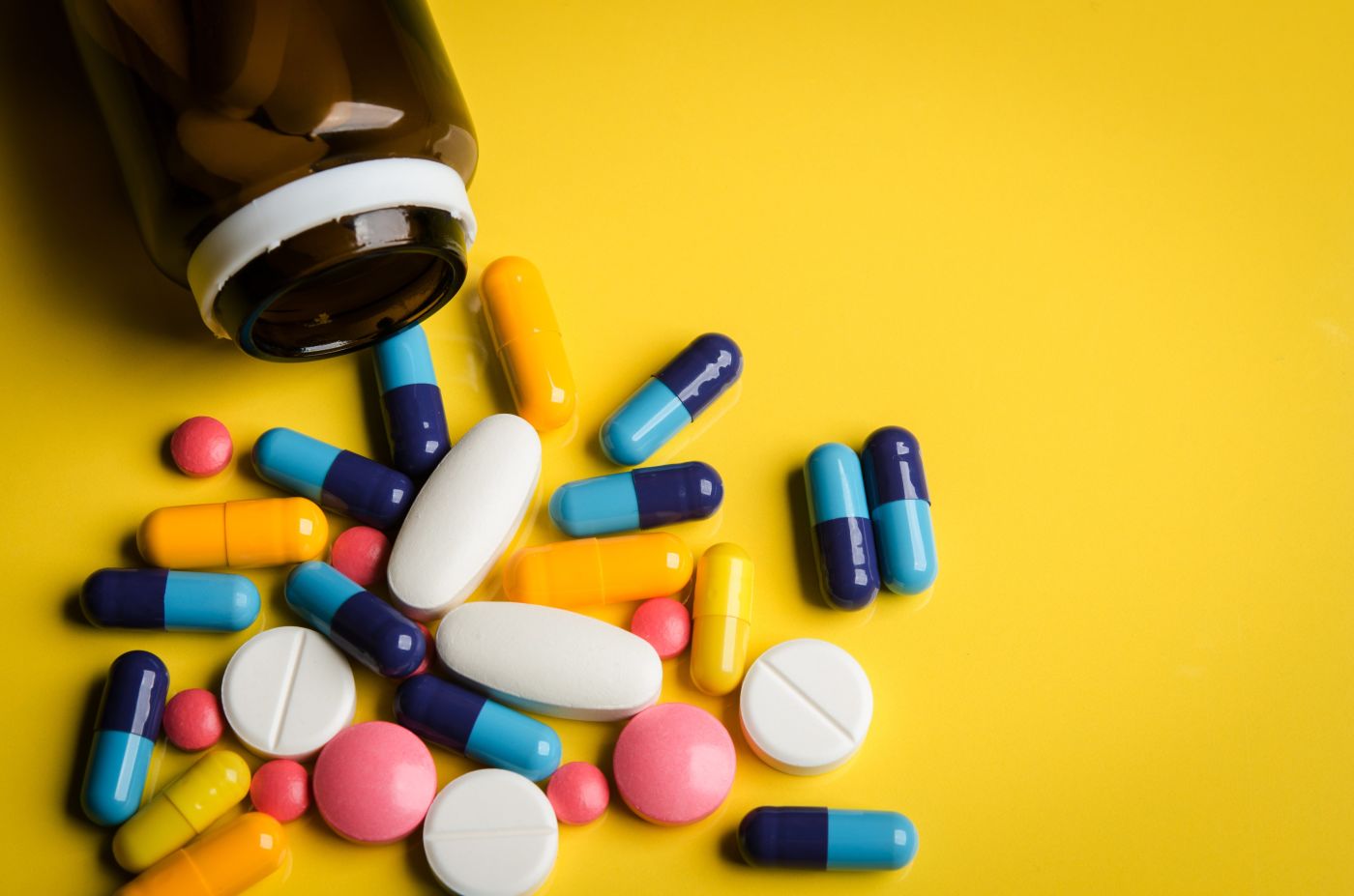 Colorful pills spilling out of a bottle