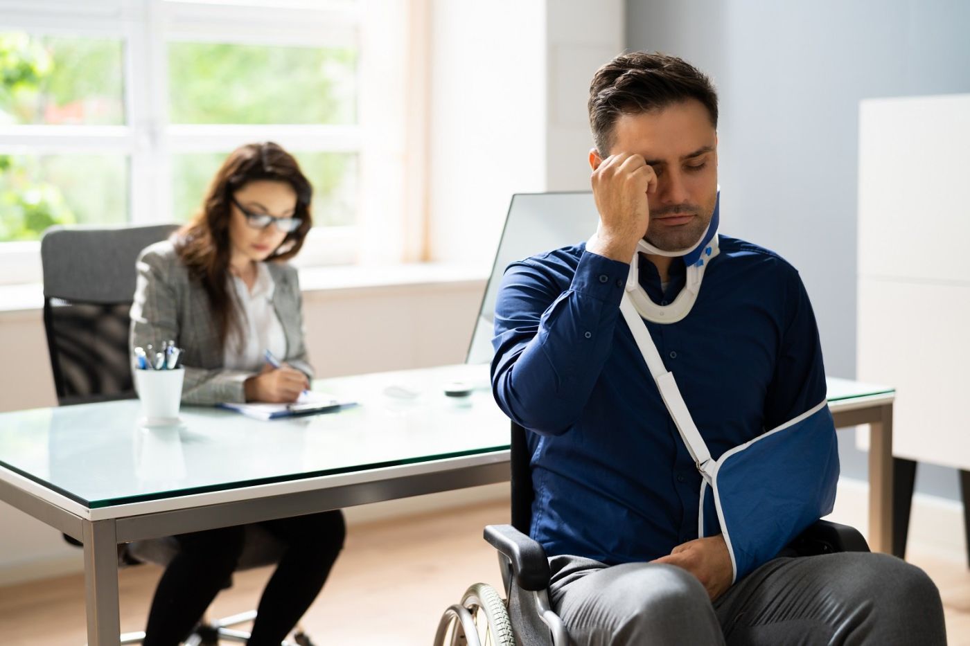 Women on laptop while man with broken arm sits in chair