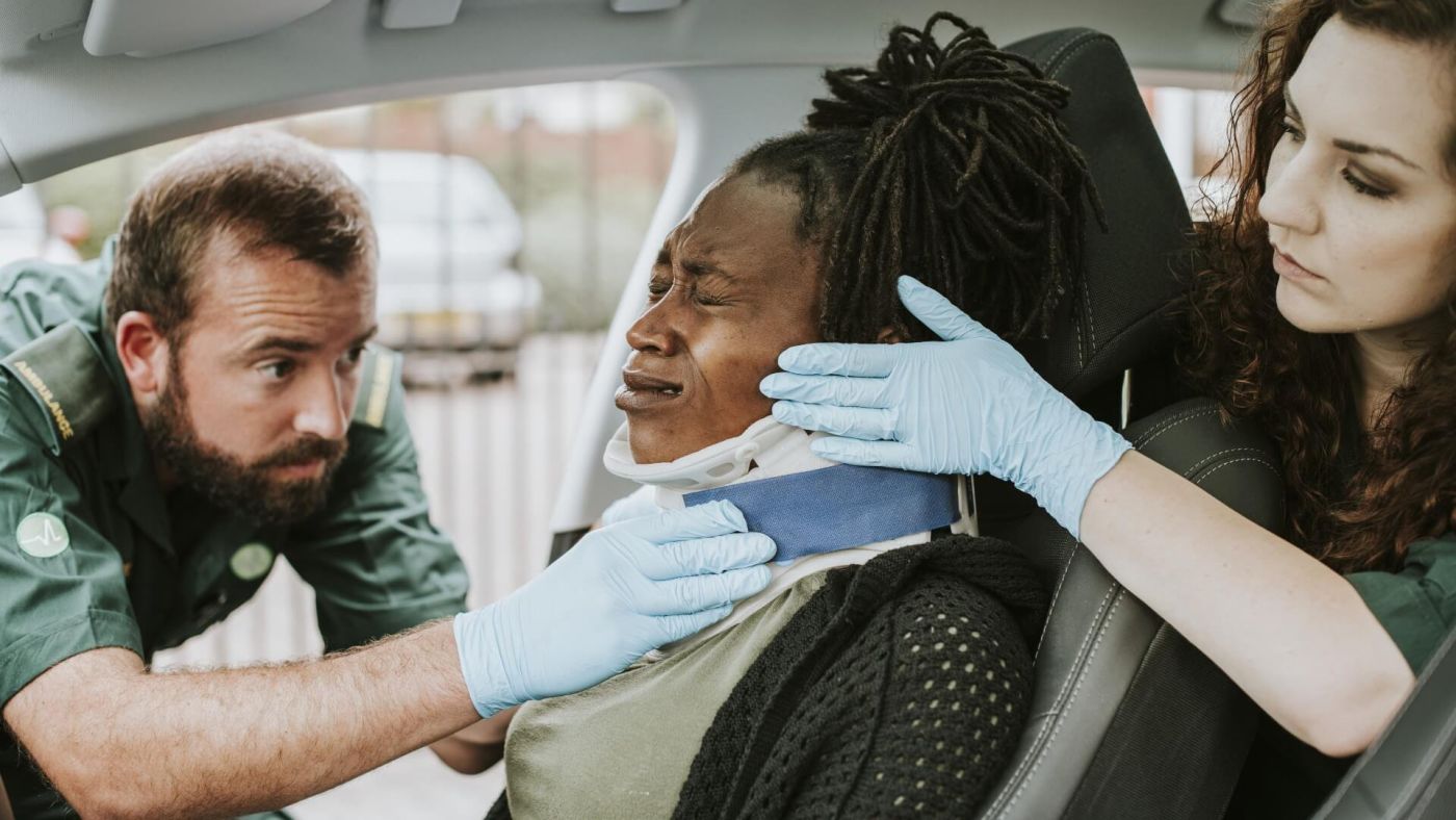 Woman in passenger seat with neck brace being treated by a paramedic.jpeg