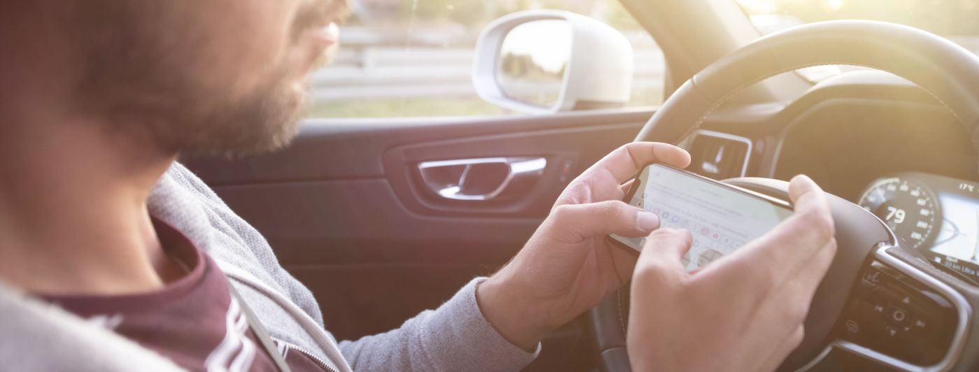 Texting while driving car. Irresponsible man sending sms and using smartphone.