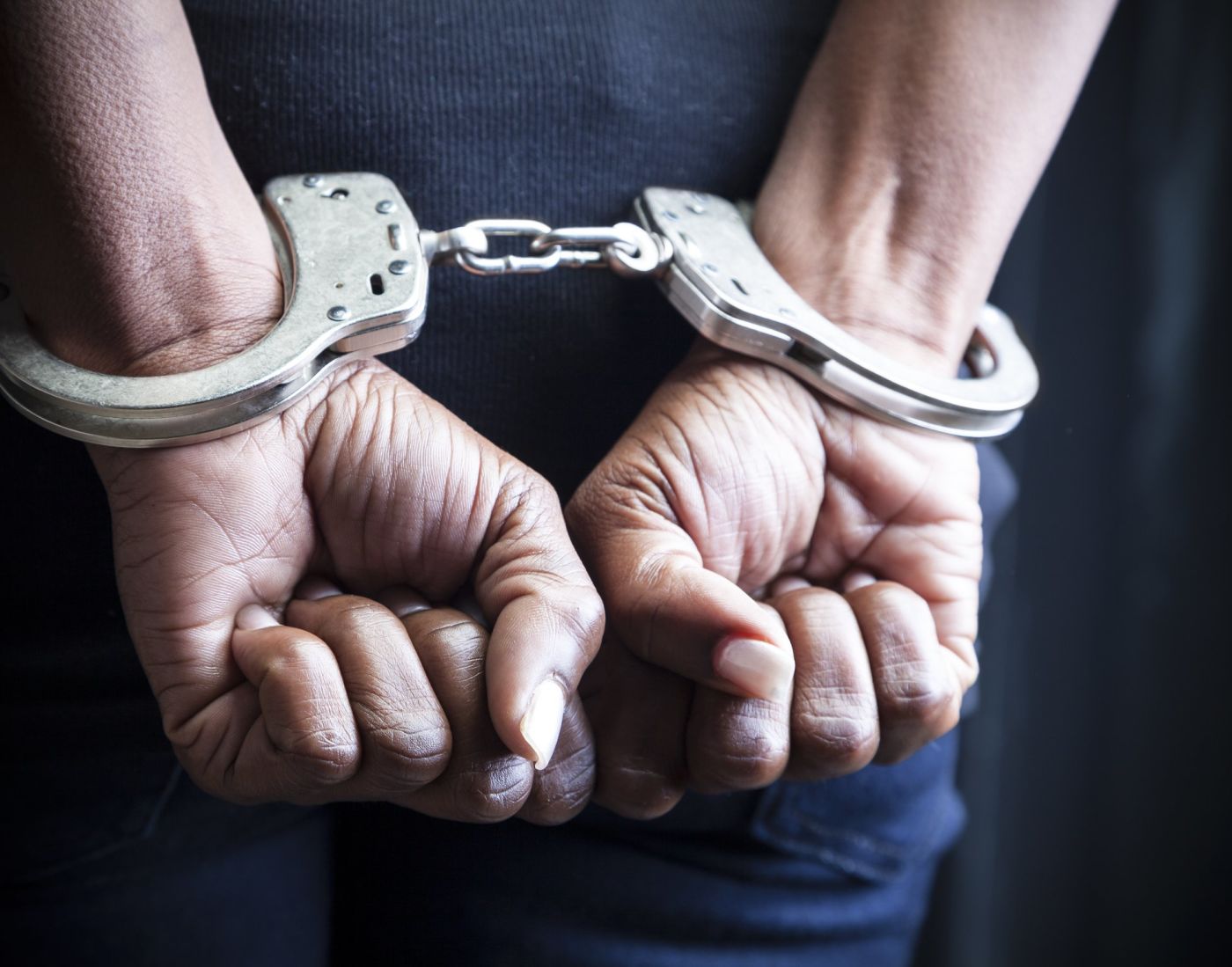 Clenched fists in handcuffs behind back