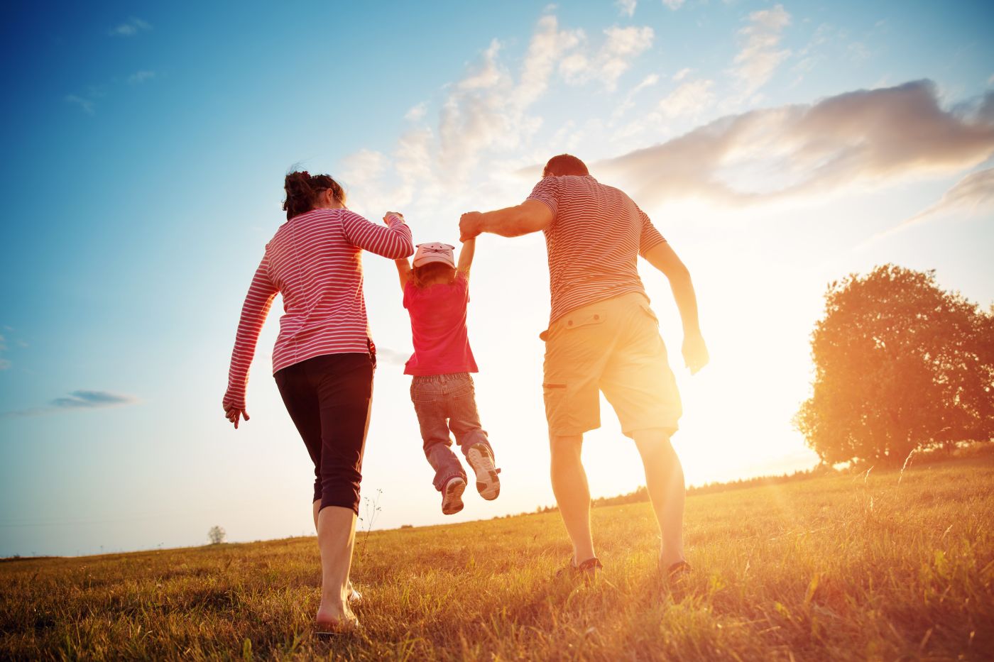 Child with mother and father holding hands in a field.jpeg
