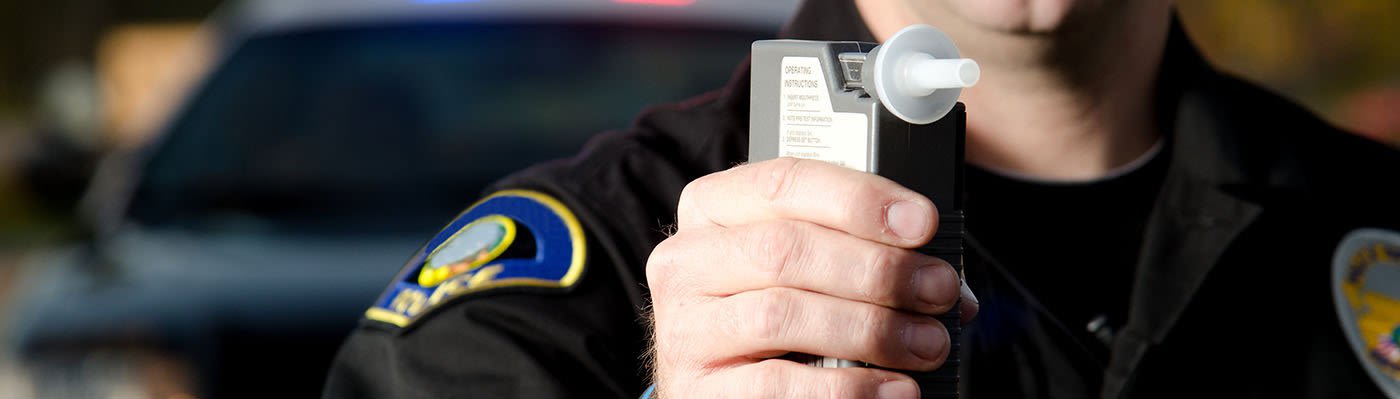 Police officer holding a breathalyzer device up