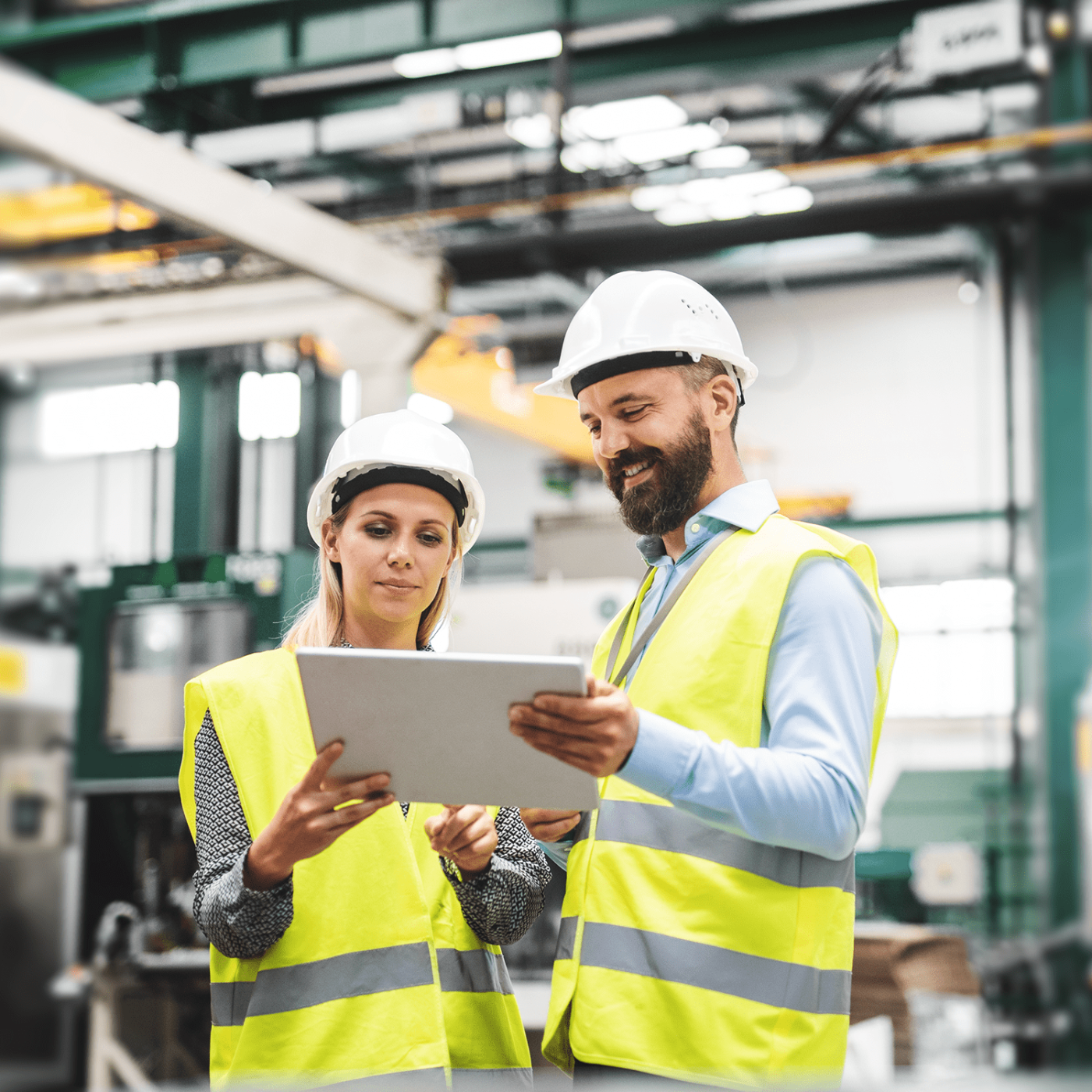 A portrait of an industrial man and woman engineer with tablet in a factory, talking.