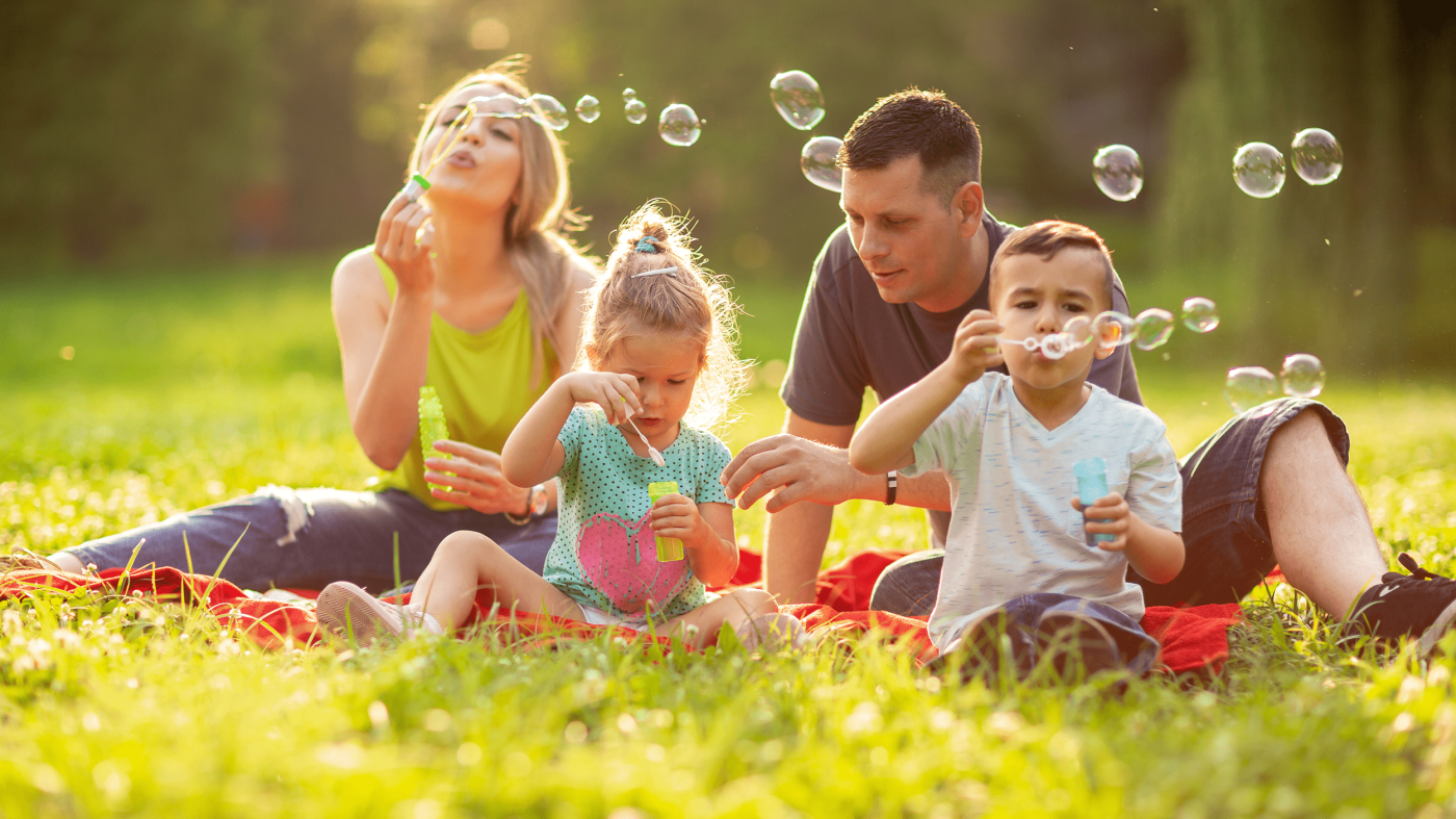 Happy family with children blow soap bubbles outdoor.