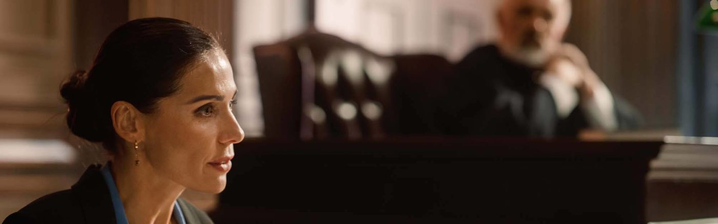 A woman talking to a jury in a courtroom with a judge present
