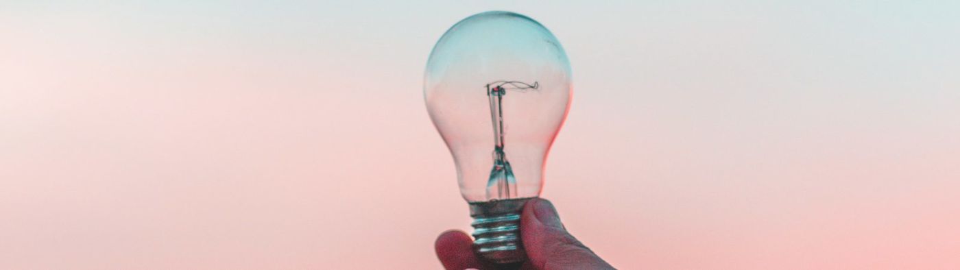 Someone holding a light bulb at dusk.