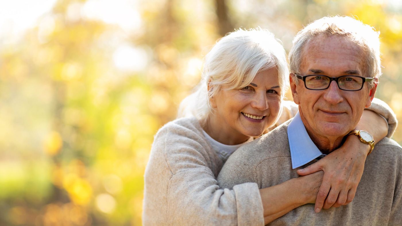 Elderly couple embracing in autumn park