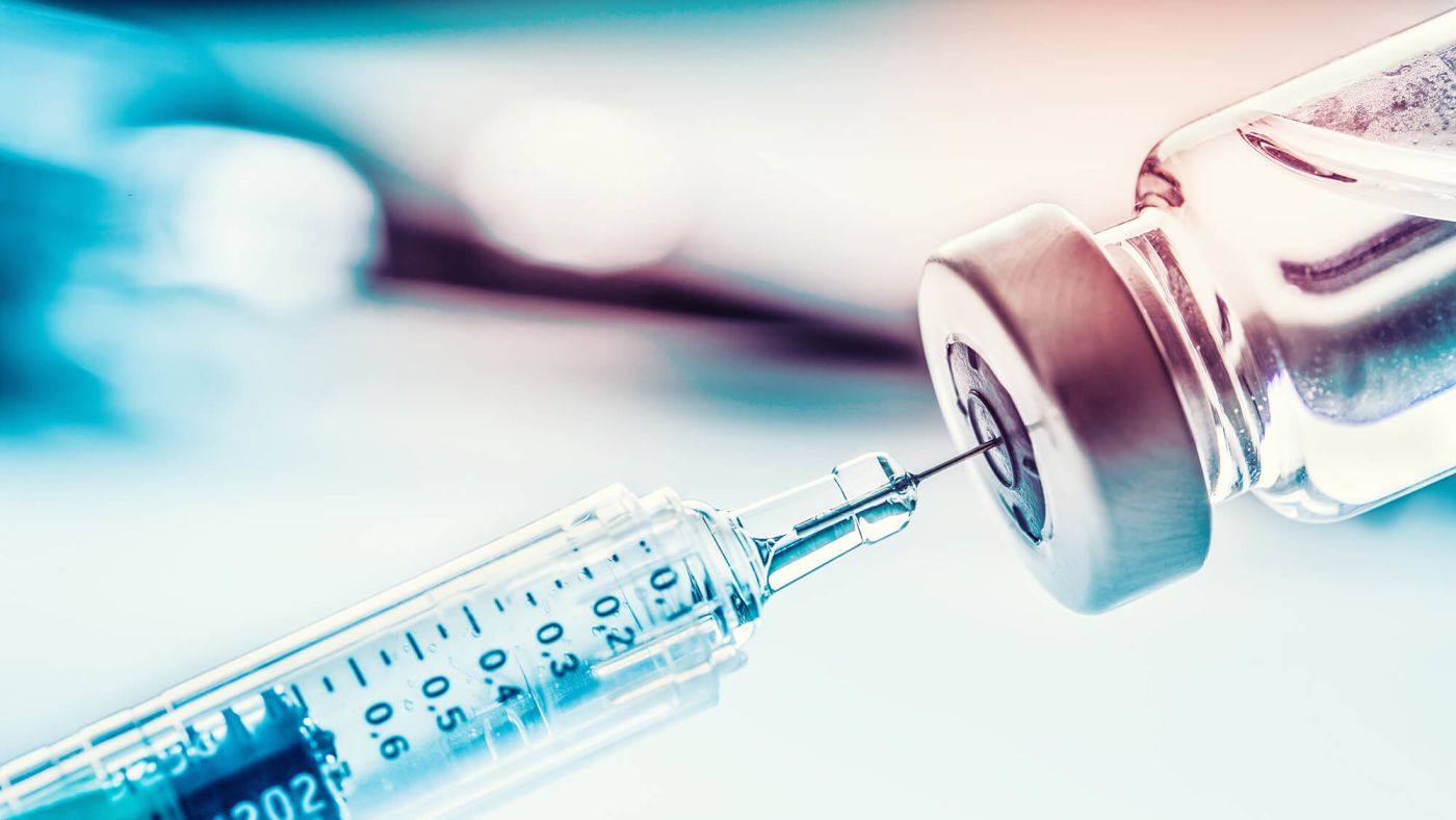 A needle going into a vial of vaccine.