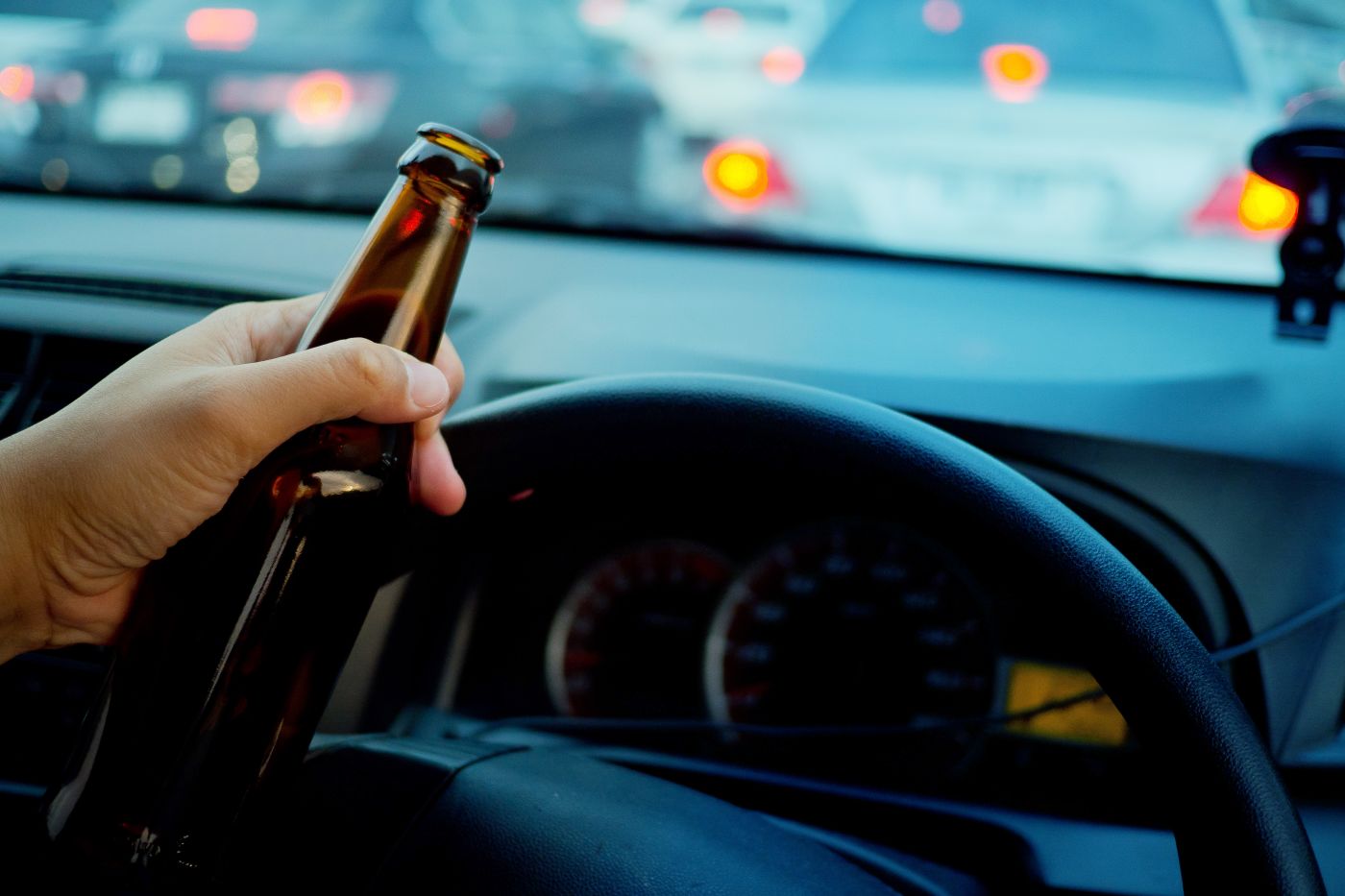 Man holding beer bottle in hand while driving car