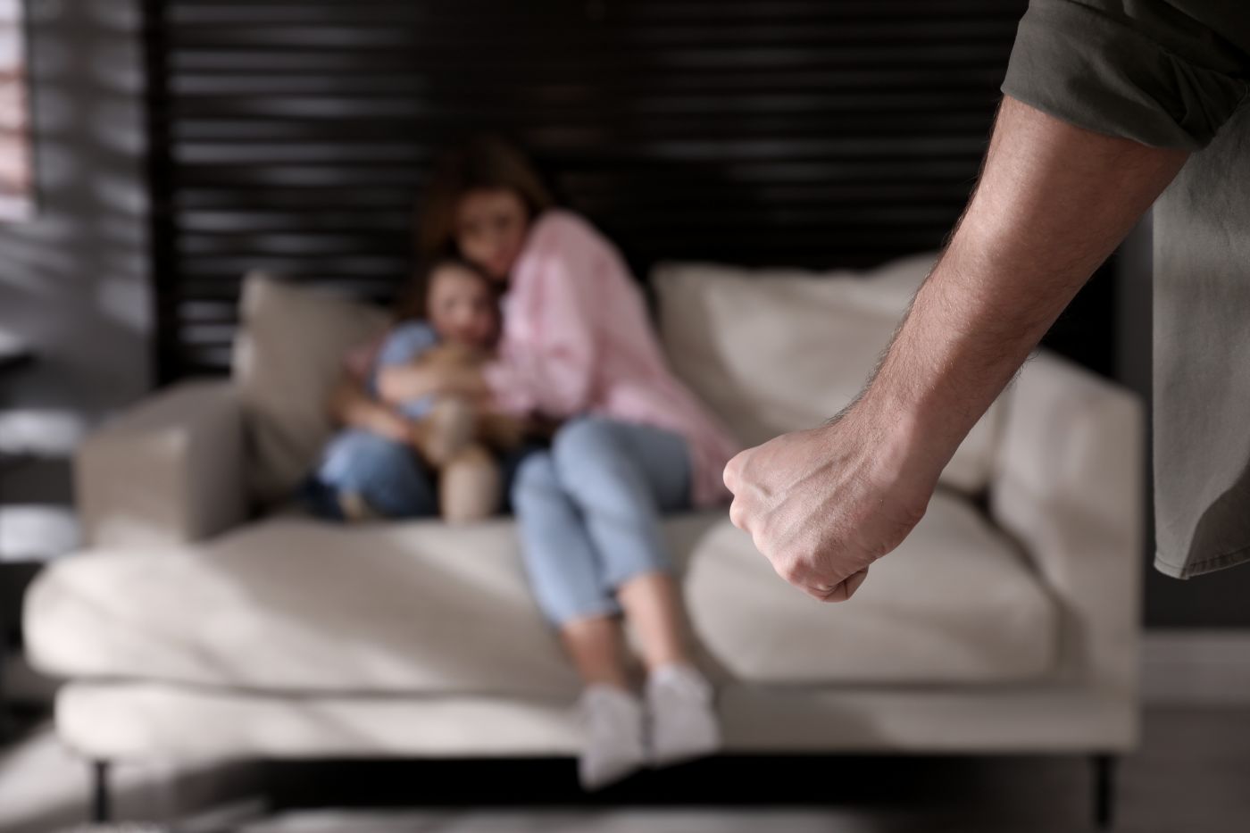 Man with closed fist and scared women and child in background