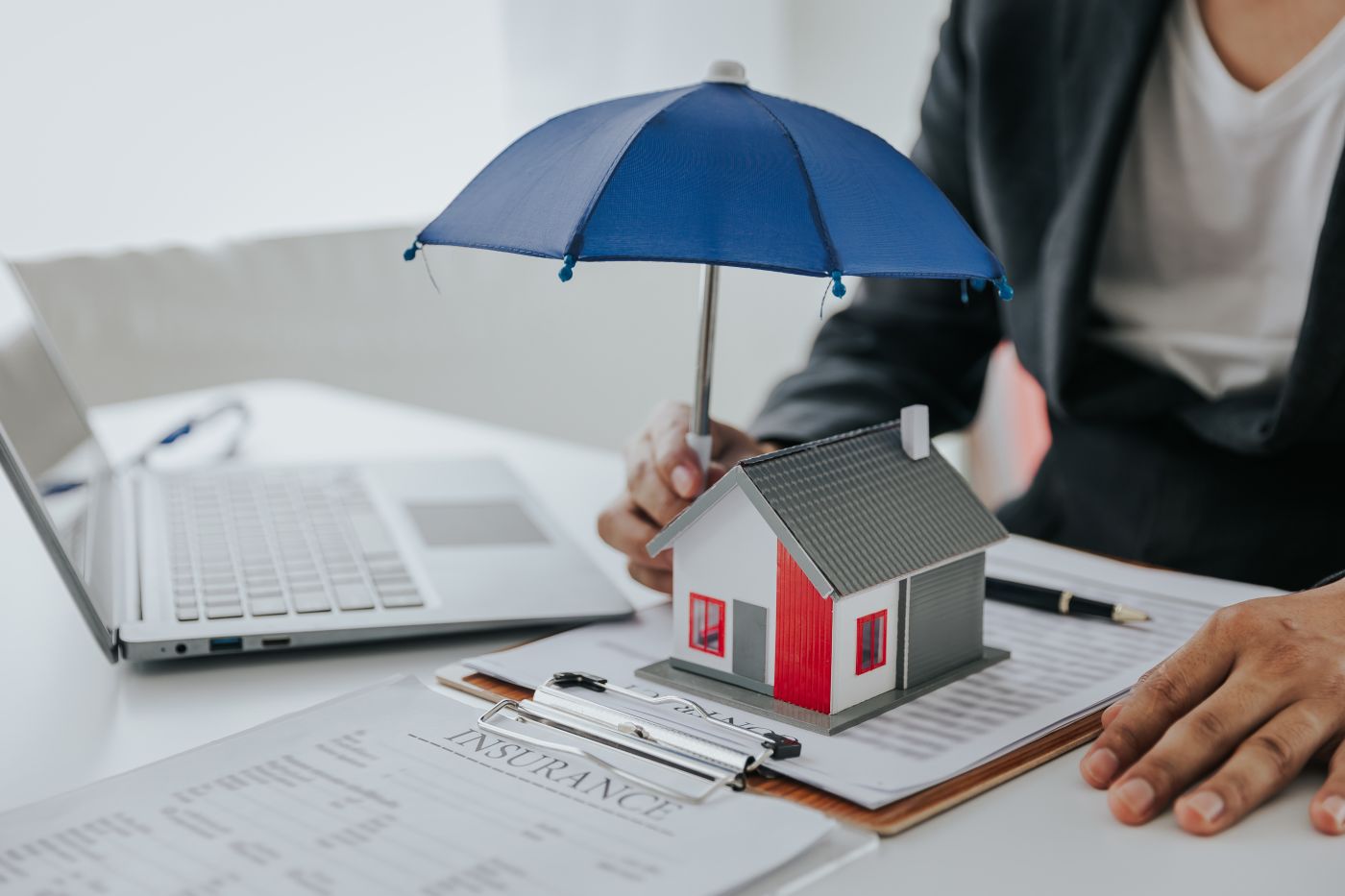 Insurance agent holds umbrella over house model