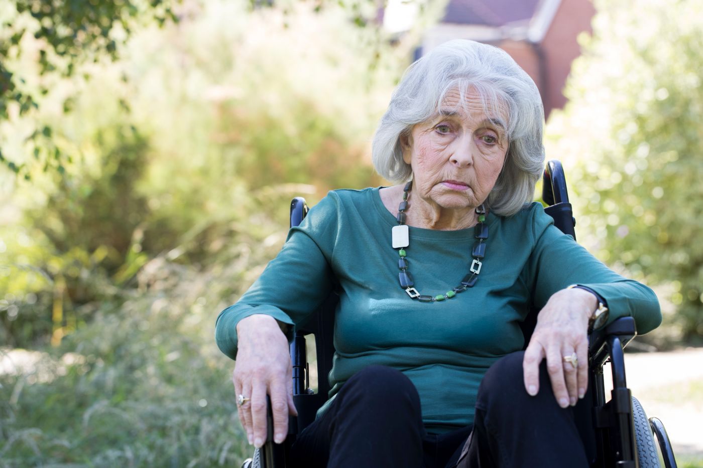 Depressed senior women in wheelchair sitting outdoors
