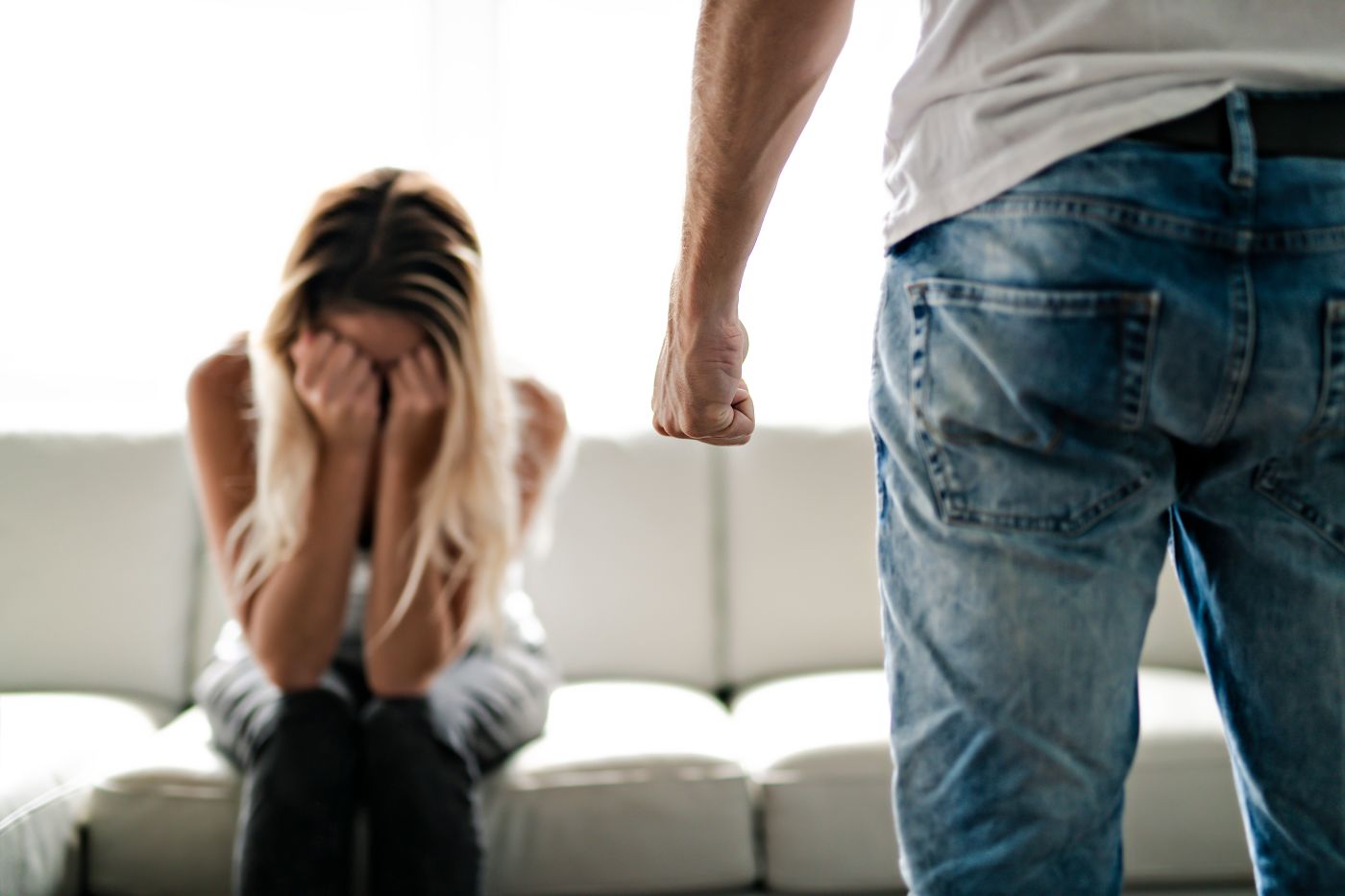 Man with closed fist and women crying in sofa