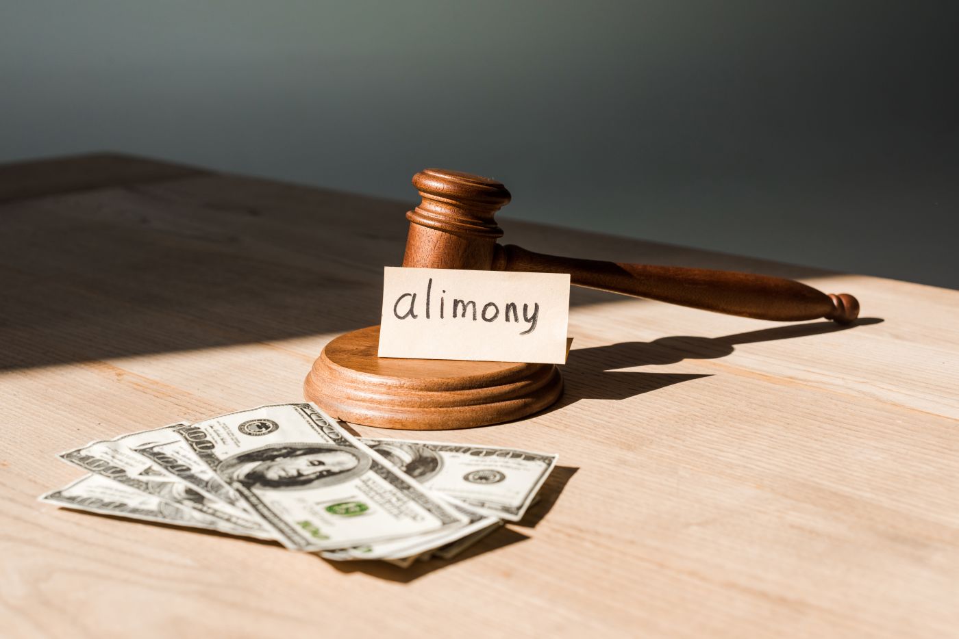 Gavel near dollar bills and alimony note