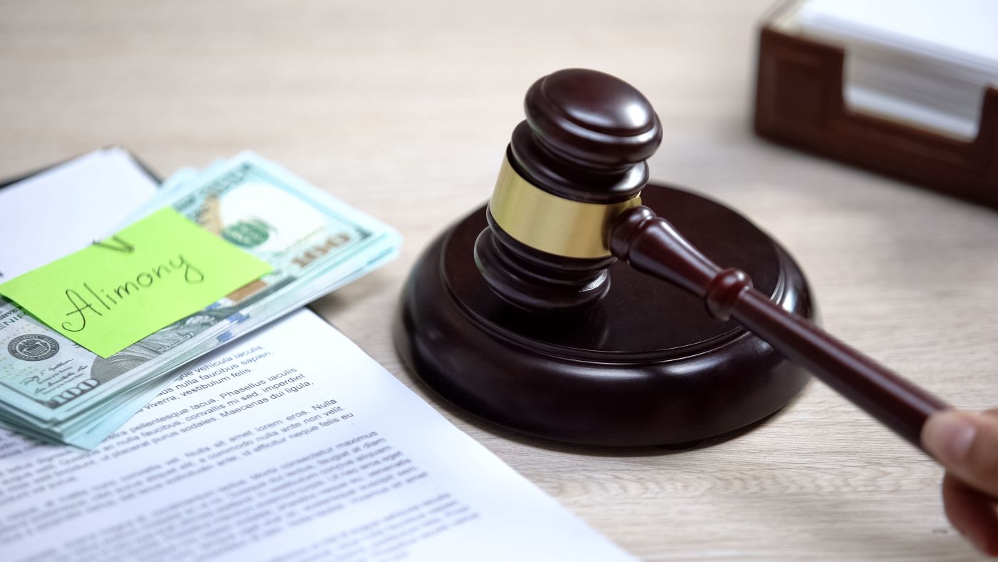 Dollar with Alimony note and gavel in table
