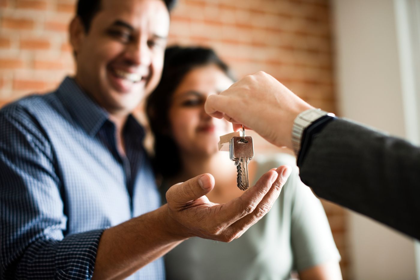 Real Estate Agent handing home keys to cheerful couple