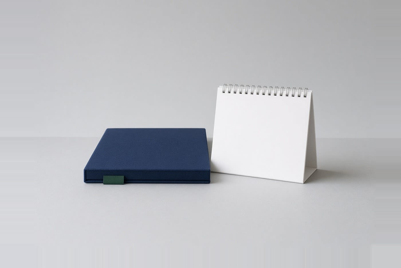 Navy folder with a green tab beside a blank desk calendar