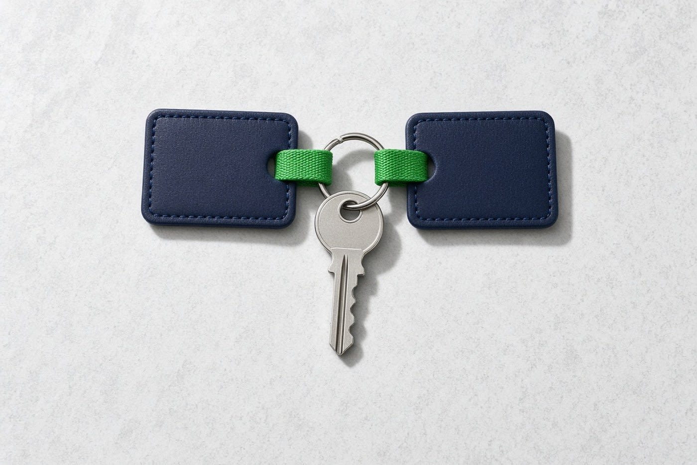Two navy key tags joined by short green loops to a ring carrying a single key