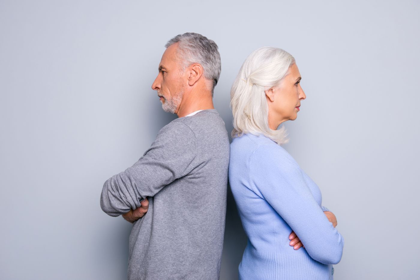 Divorcing senior couples standing back-to-back
