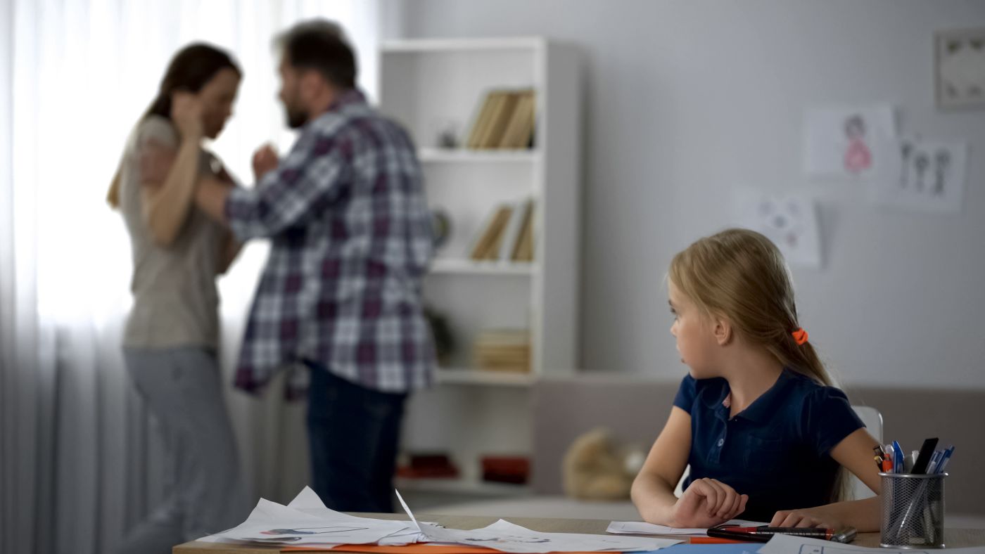 Worried child looking at father showing aggression towards mother